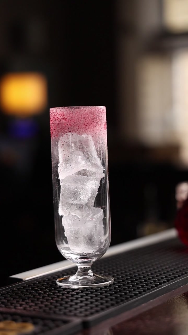 Bicchiere da cocktail vuoto con bordo di zucchero rosso e cubetti di ghiaccio