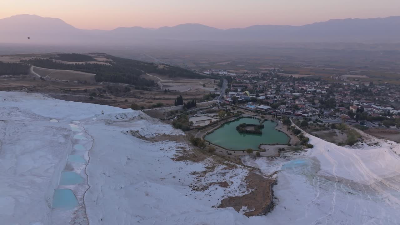 Pamukkale'nin güneşli traverten terasları üzerinde süzülen yamaç paraşütçüleri.
