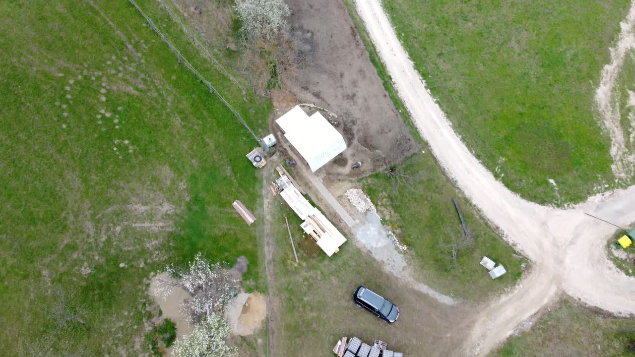 Ovenfra udsigt fra en drone over et landsted, vej og græsgang.