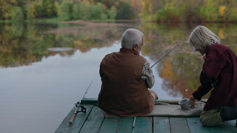 elderly couple fishing on a tranquil lake dock in autumn