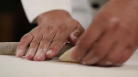 hand rolling chinese dumplings with a wooden rolling pin - side view