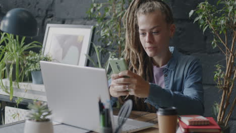 woman working on laptop and phone in a modern office