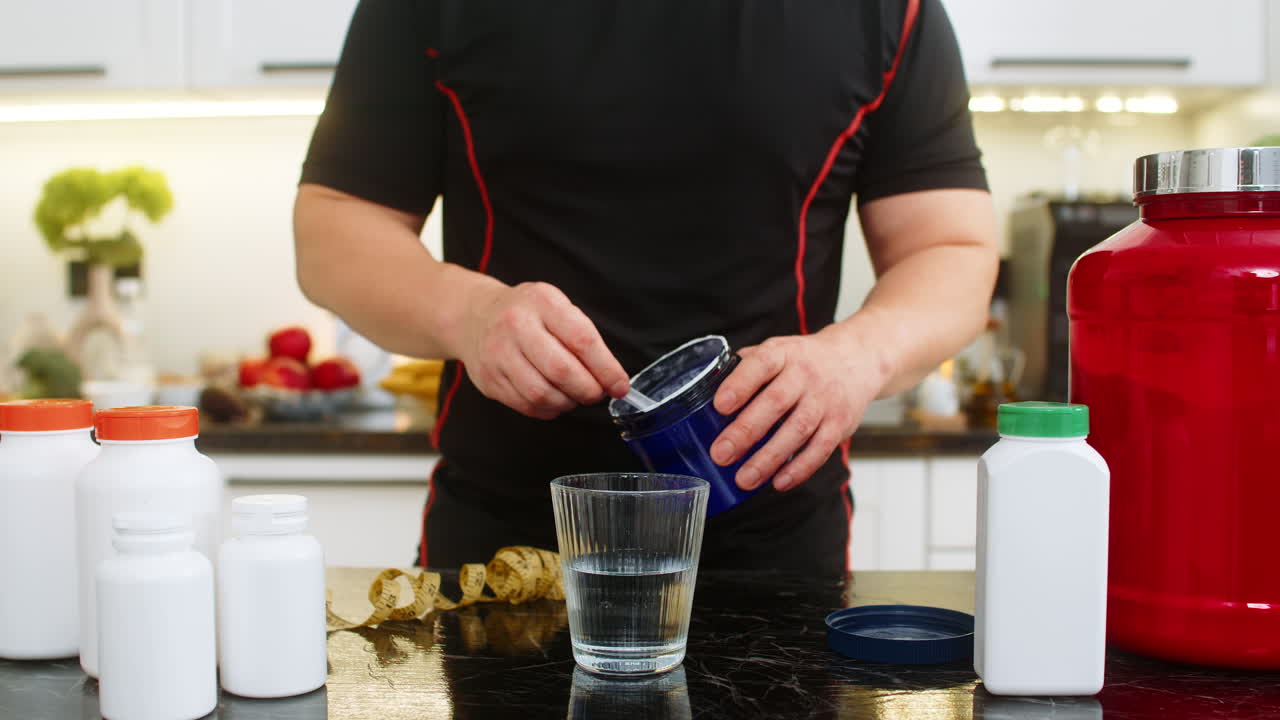 Sportsman pours supplement powder into glass of water in kitchen at home for daily fitness energy up