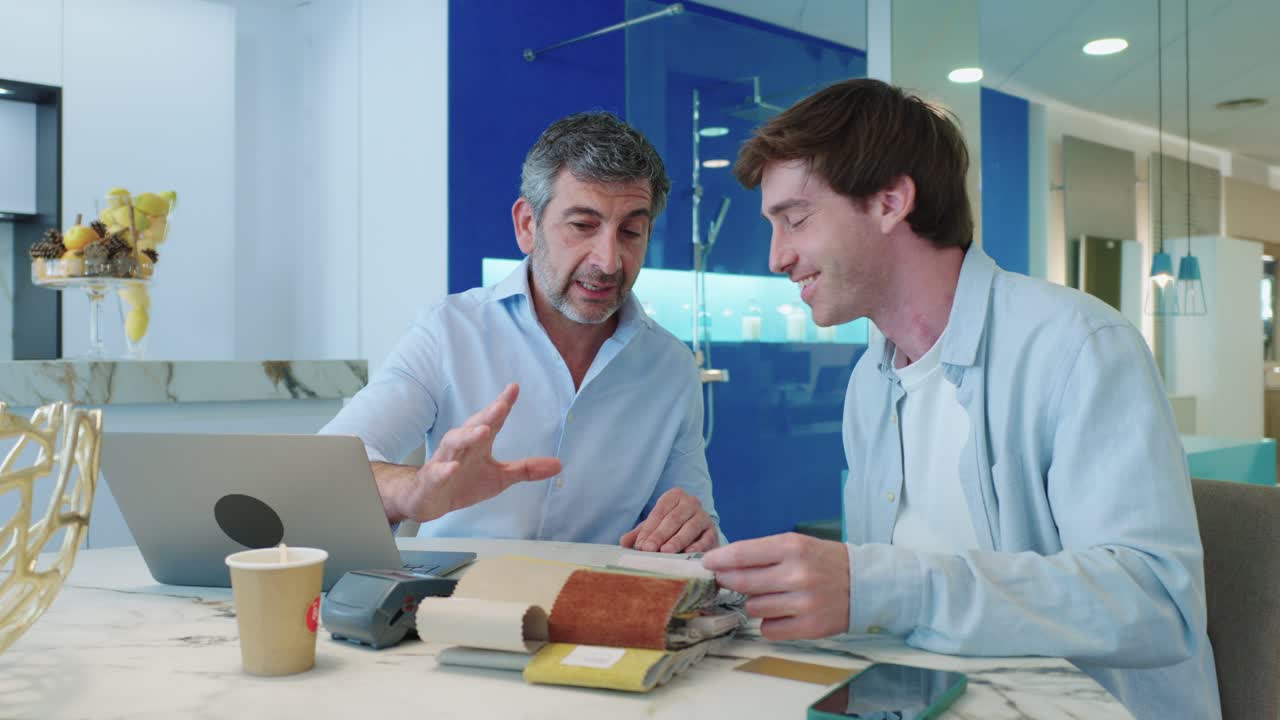 Two men discussing fabric samples at a table