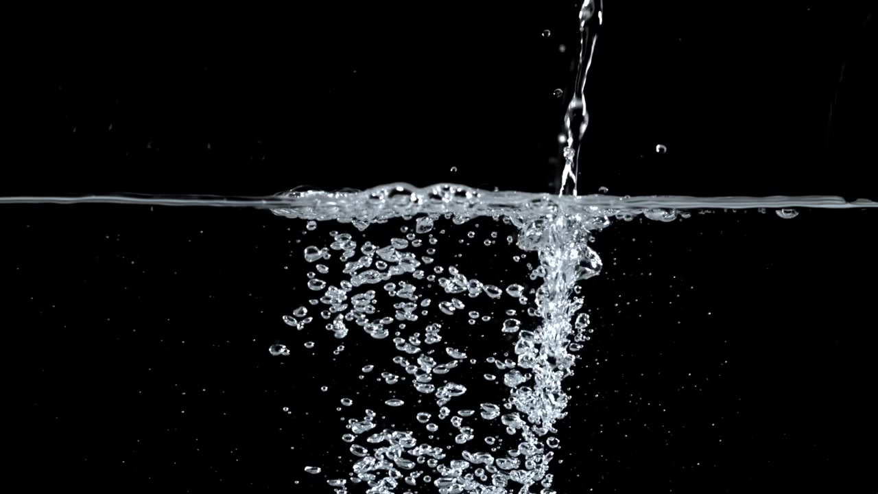 Acqua che si versa e ribolle su sfondo nero.