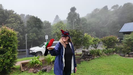female tourist interacts with tropical birds at a hinterland getaway on a misty fog covered morning