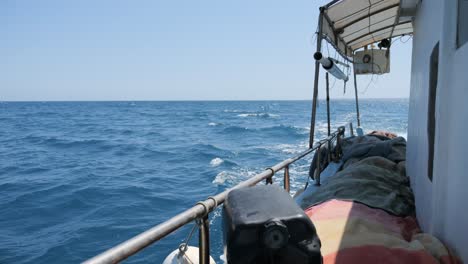 slow motion view down the starboard side of a fishing boat as it rides through open waters