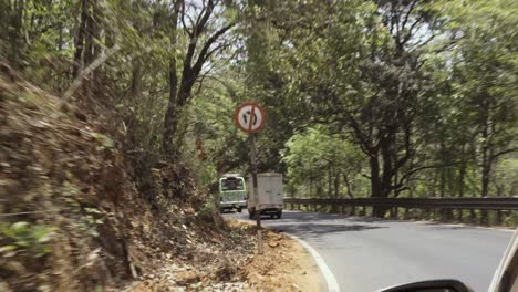 riding at a tropical road in goa, india, behind a white truck, green tropical forest