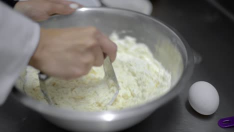 Woman-chef-baker-mixing-kneading-dough-with-a-metal-cuter-blender-in-a-metal-bowl-at-a-local-bakery-restaurant-in-Mexico-latin-america