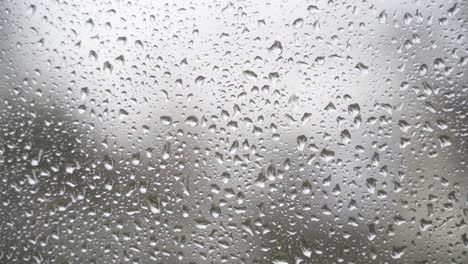 a steady 4k close-up of a window on a rainy day.
the small, aesthetic raindrops slowly run down the window pane.