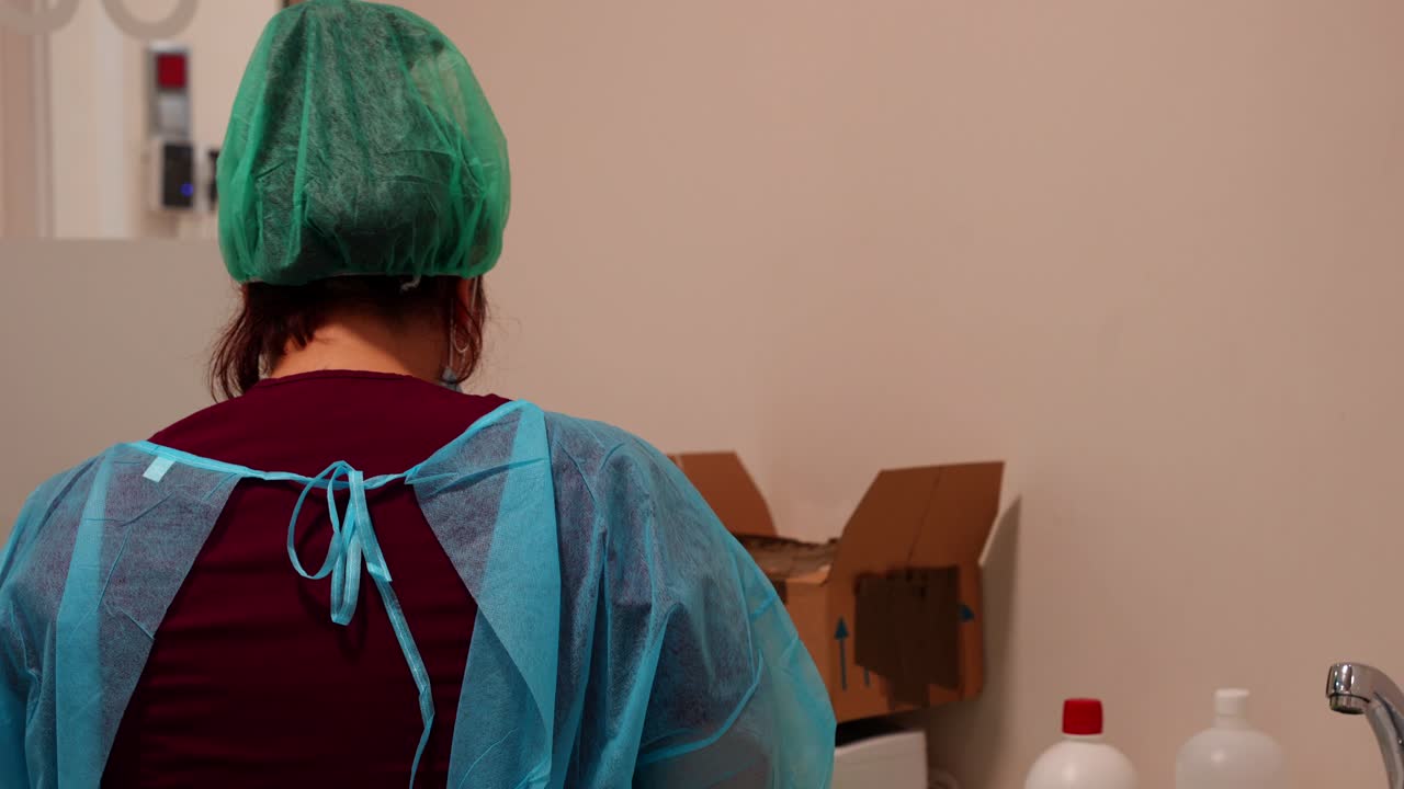 higiénico con traje de protección personal y gorra desechable limpiando instrumentos médicos en el fregadero