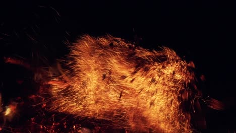 flaming wood and flying sparks. contrasting view of flaming logs against a black background. fiery flame and smoke winding around the wooden remains