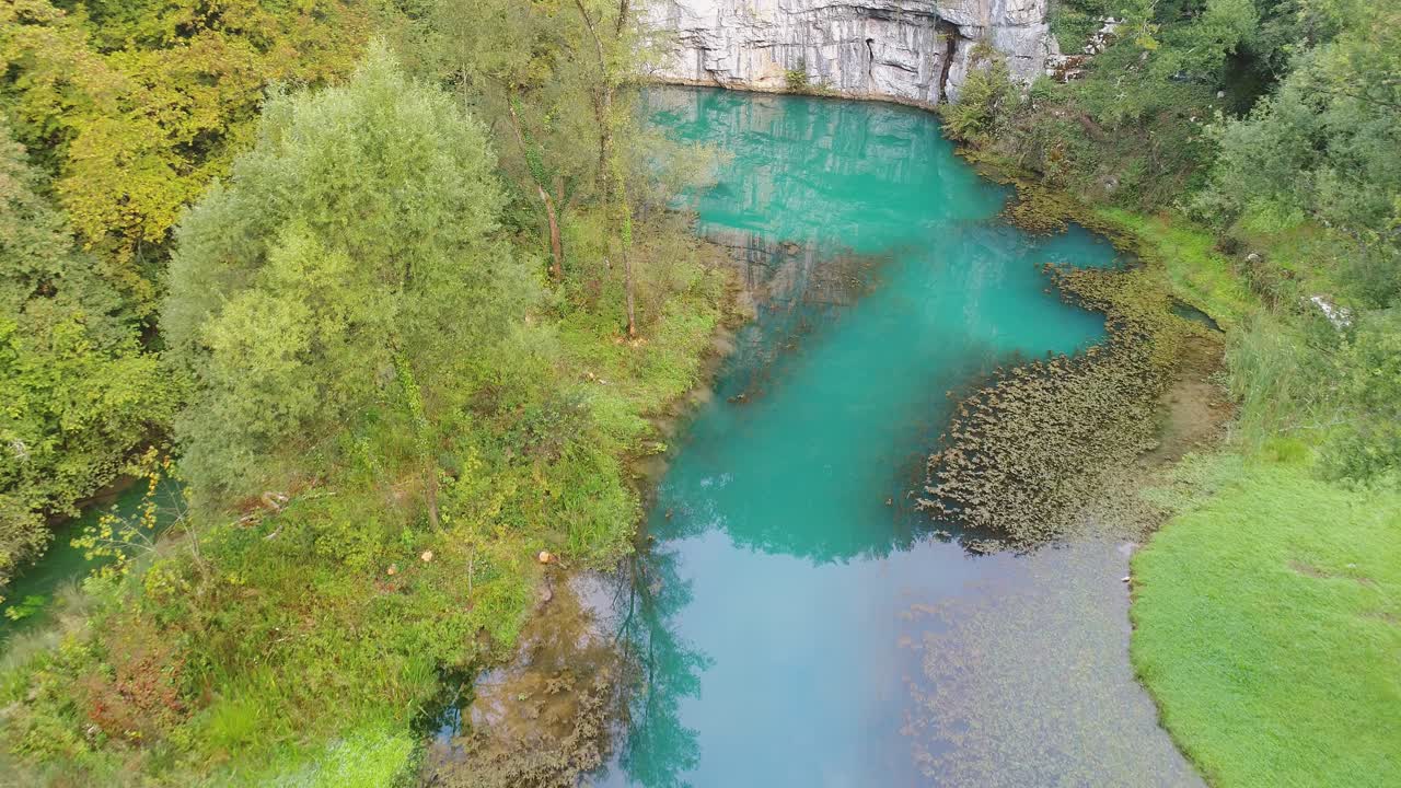 Aerial view of PCB polluted waters of Krupa river under rock wall amidst dense greenery in Semic, Slovenia