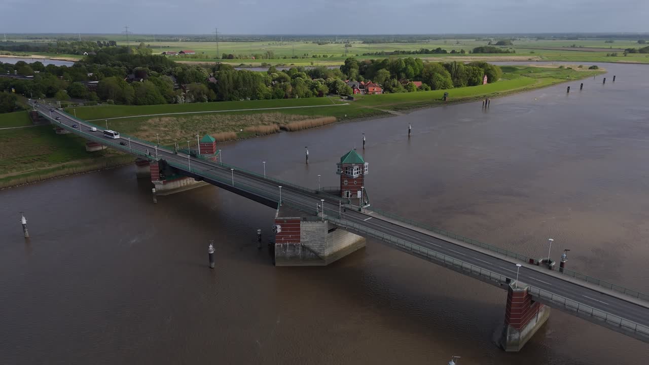Smooth drone orbit of the Jann Berghaus Bridge crossing the Ems River near Leer. Captures road traffic, riverside landscape and architectural features of this bascule bridge in Northern Germany.