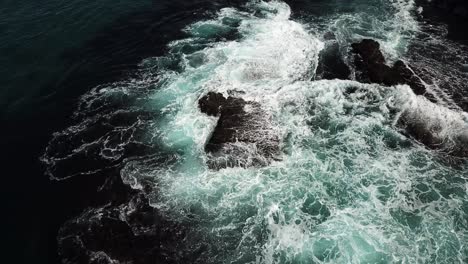 aerial view of ocean waves crashing on rocky coastline