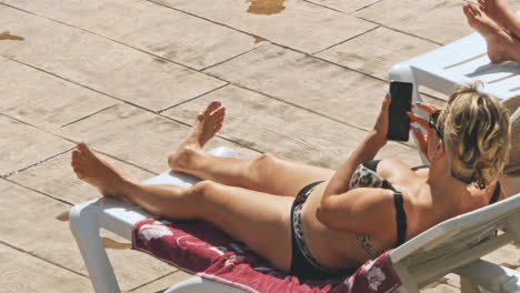 mujer tomando el sol en una silla junto a la piscina