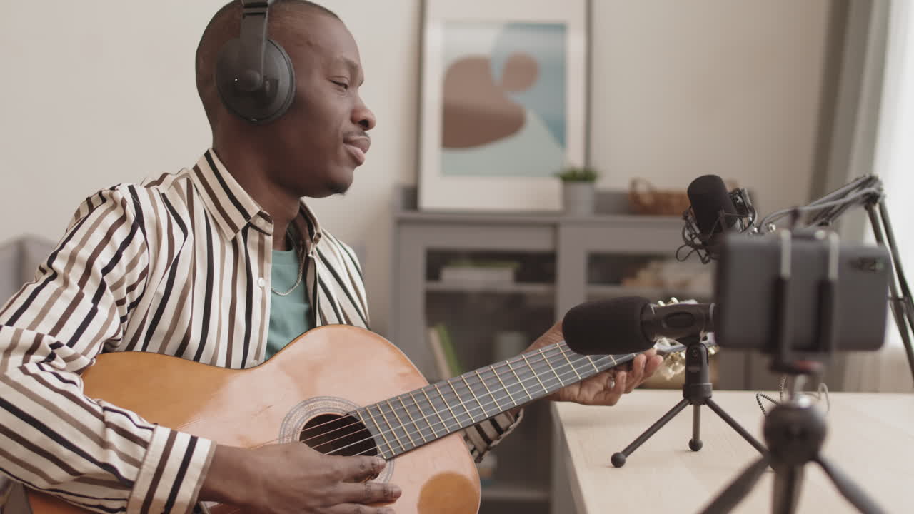 Man Playing Guitar and Recording Music
