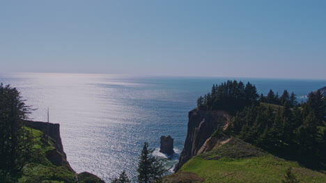 aerial rising from meadow revealing ocean, steep cliff, trees, rock