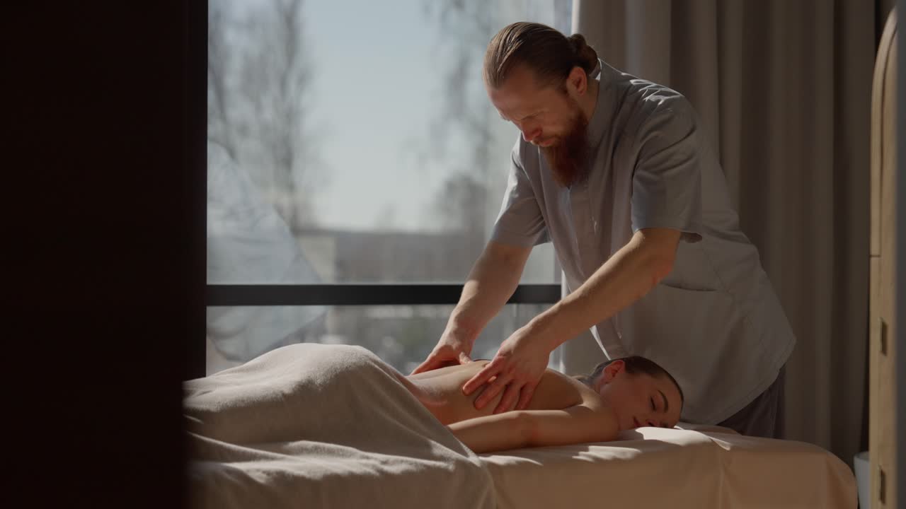 Người đàn ông mát xa lưng thư giãn cho một phụ nữ tại spa