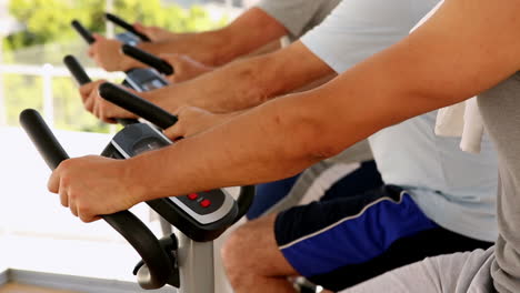 Three-men-working-out-on-exercise-bikes