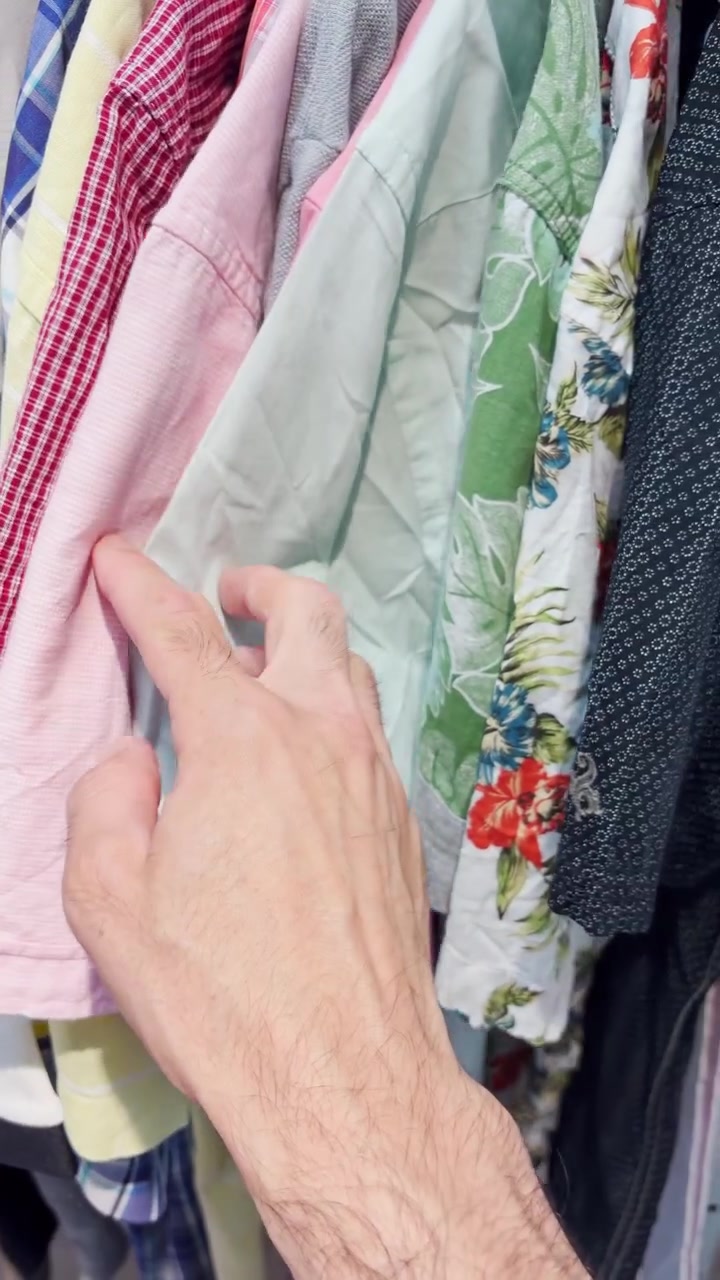 POV hand browsing and looking at second hand vintage clothes in store or market. Zero waste shopping for hipster retro fashion treasure hunt. Vlogger in thrift store sustainable lifestyle UGC video