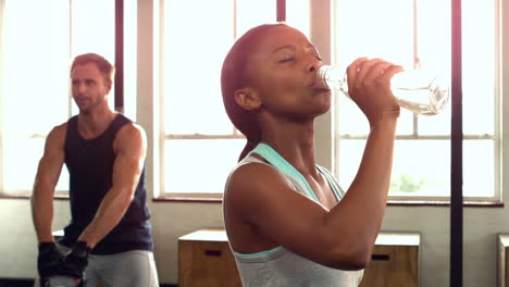 fit woman drinking water in fitness studio