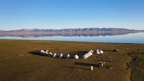 Rotating-drone-shot-of-a-small-yurt-village-beside-the-Song-Kol-lake-in-Kyrgyzstan