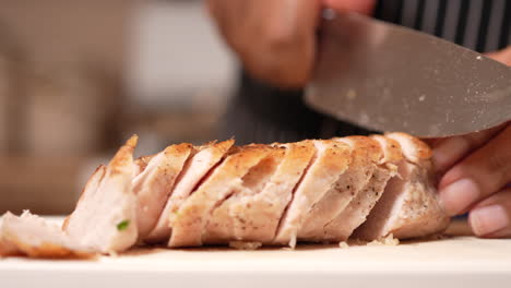 hands seen slicing cooked chicken breast for a family meal