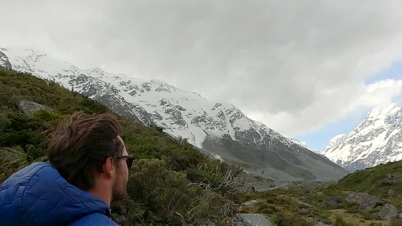 Uomo solitario che cammina verso le cime innevate e il ghiacciaio del Monte Cook in Nuova Zelanda