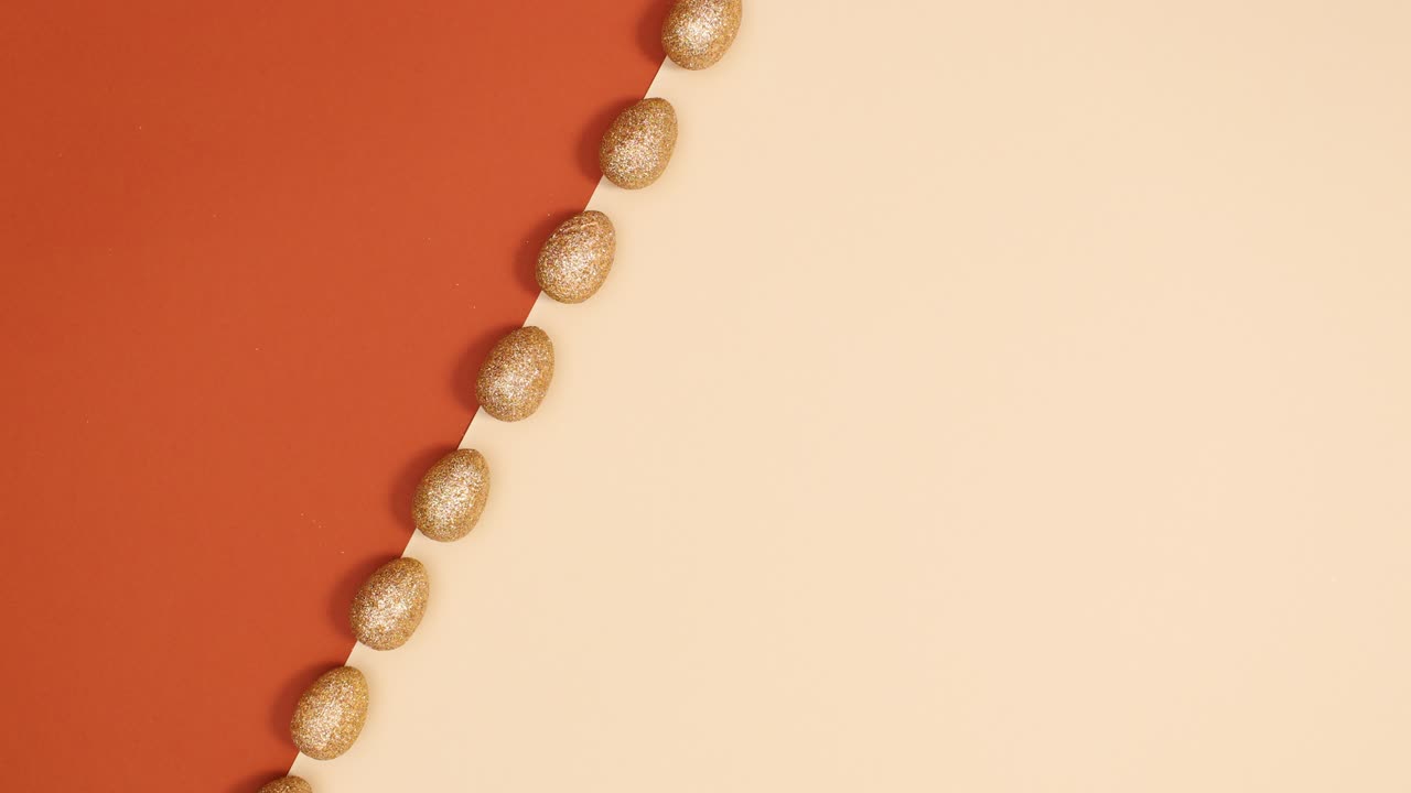 Easter gold glitter eggs appear on nude red background. Stop motion minimal flat lay