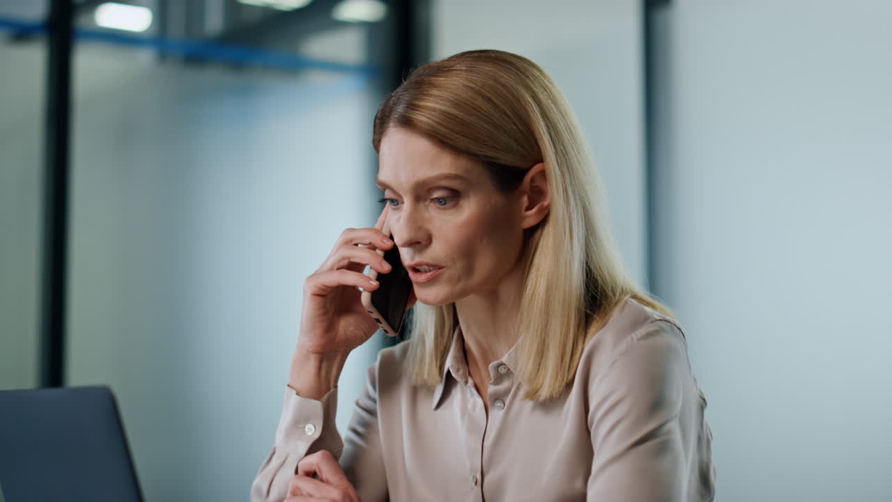 Confident businesswoman talking cellphone in office. Serious manager calling