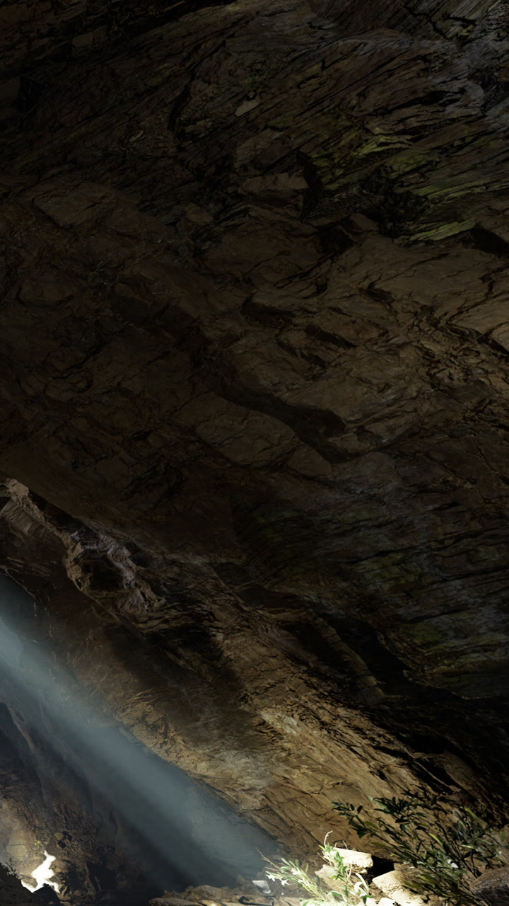 Light shines through a cave opening in a rocky landscape during the day