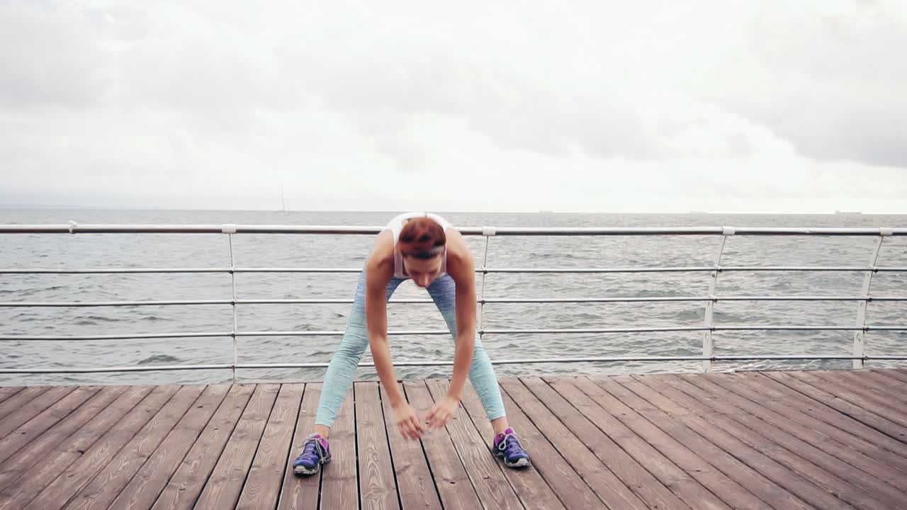 corredora mujer estirando y haciendo arcos lado. atleta femenina de fitness relajándose en la playa haciendo un calentamiento antes de su entrenamiento de cardio