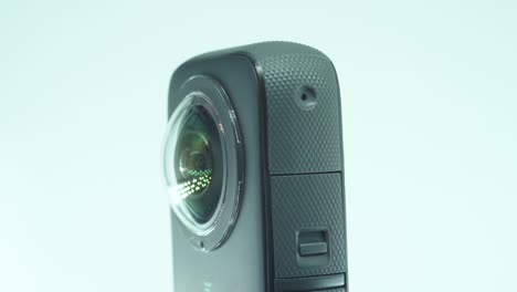 un primer plano de una cámara 360 con lente dual, dos cubiertas de lentes, iluminación de estudio brillante que refleja, en un soporte giratorio, cámara lenta, video de 4k