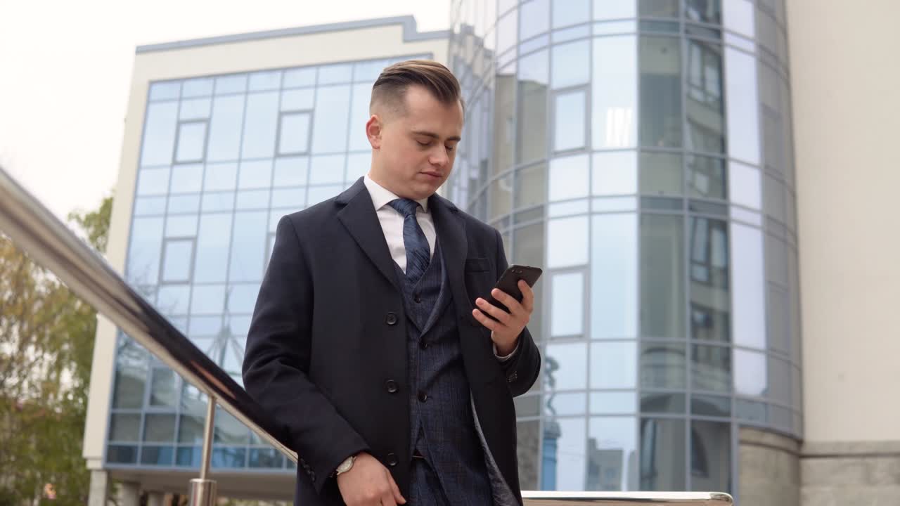 Handsome startup businessman using mobile phone. Young man texting messages, cheating on his smartphone near the office center. Business. Social Networking