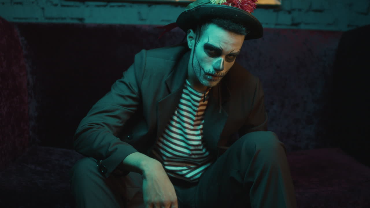 молодой человек сидит и смотрит в камеру.