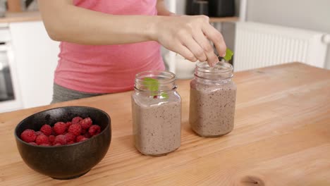 Teil-Einer-Frau,-Die-Den-Smoothie-In-Der-Küche-Dekoriert