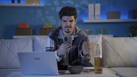 el joven que está enviando mensajes de texto por teléfono por la noche está bebiendo alcohol.