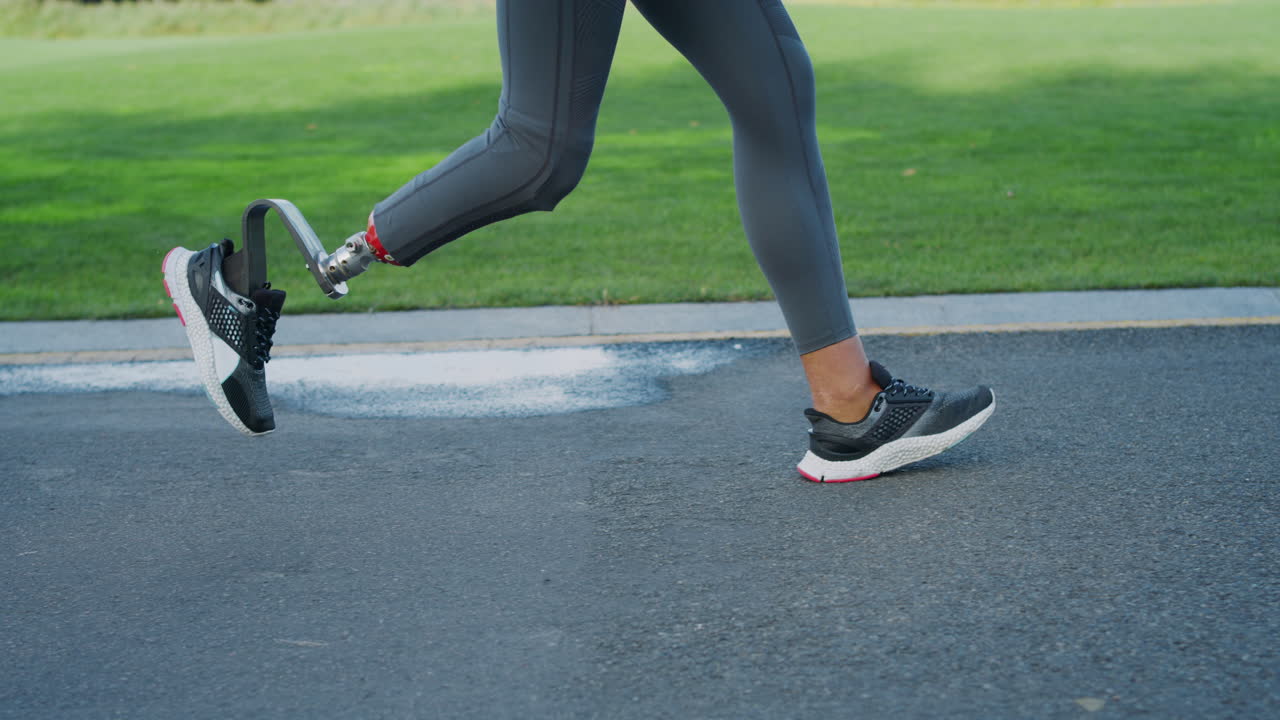 Donna con protesi alla gamba che corre sulla strada. Atleta donna che si allena all'aperto.