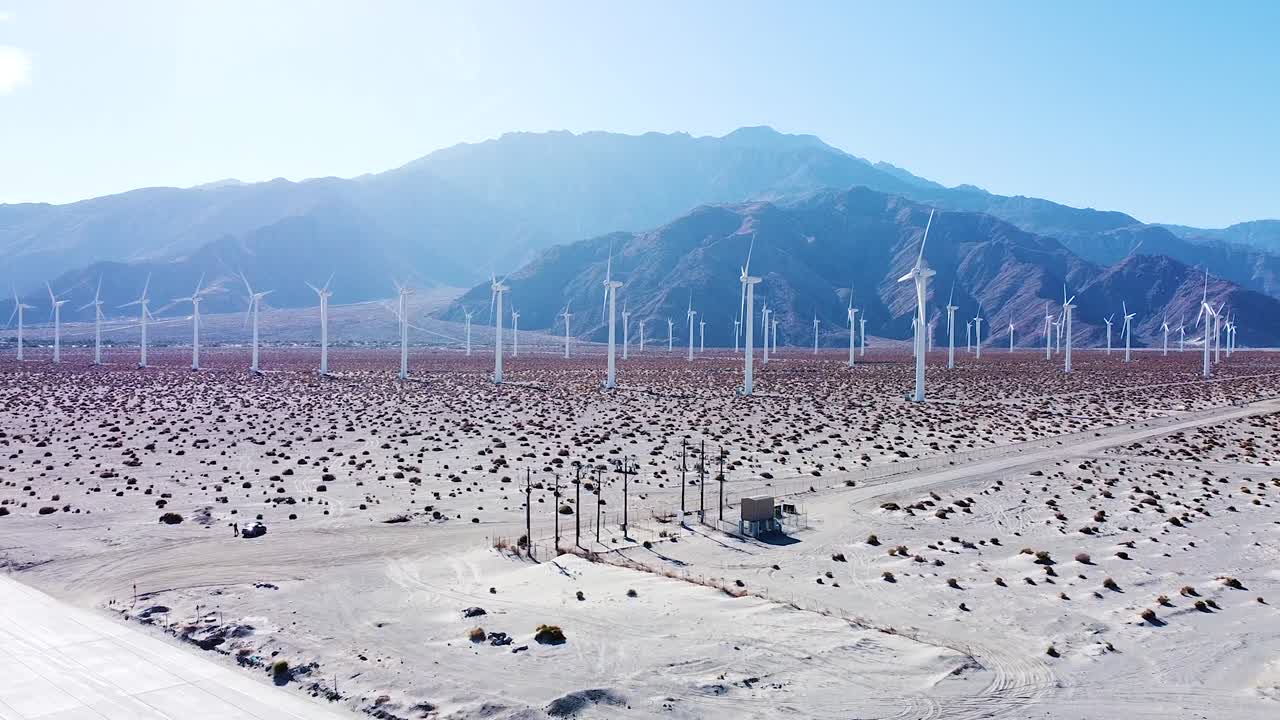 장엄한 산맥을 배경으로 한 사막 지역의 전기 풍차 농장, 공중 드론 전망