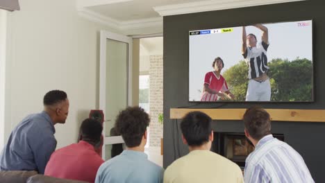 diverse friends supporting and watching tv with diverse male soccer players playing match on screen