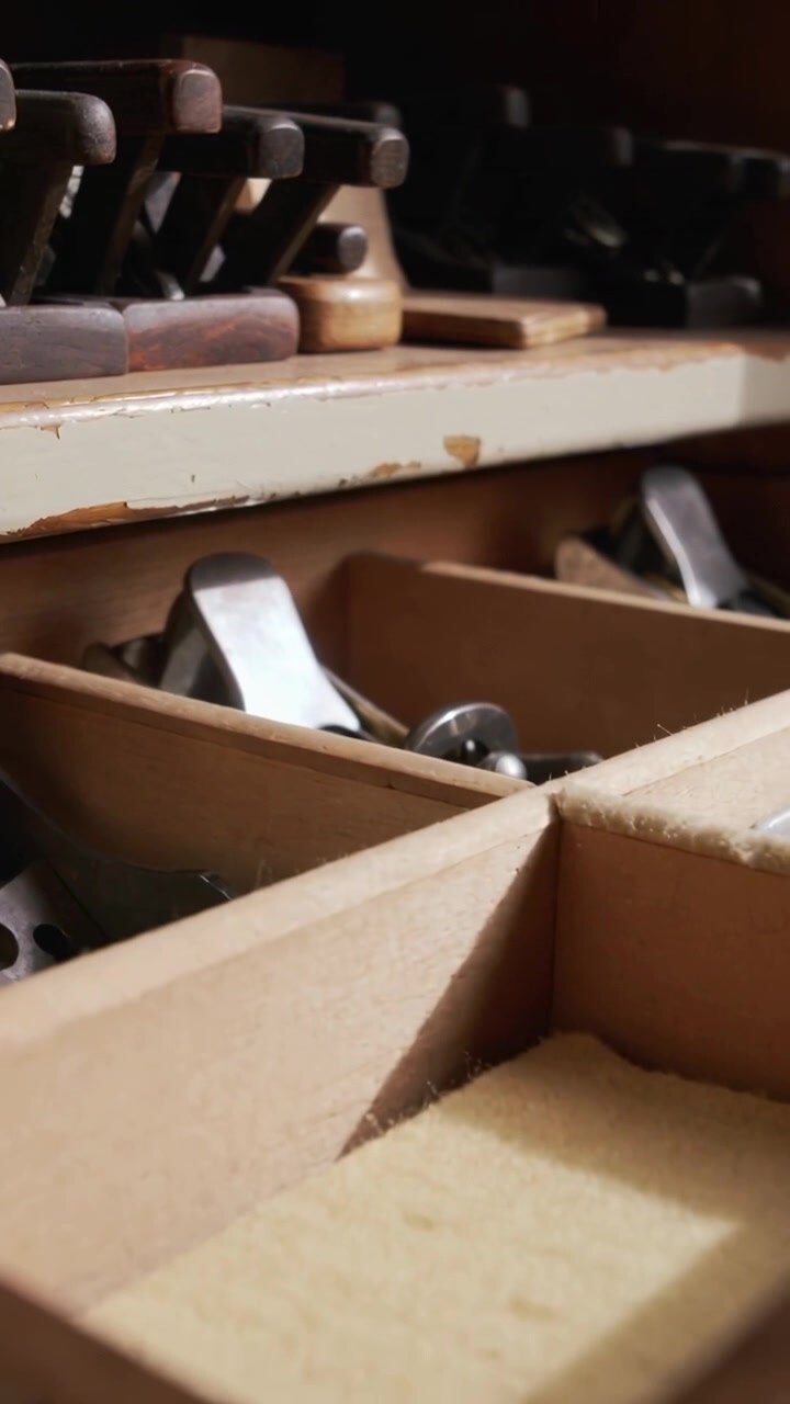 Vertical video: Panning camera after shift showing wood drawer at shop with plane irons for study