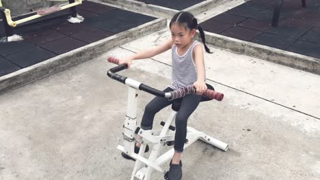 Niña-Asiática-Está-Haciendo-Ejercicio-Con-Una-Máquina-En-Un-Parque-Público-En-Bangkok,-Tailandia