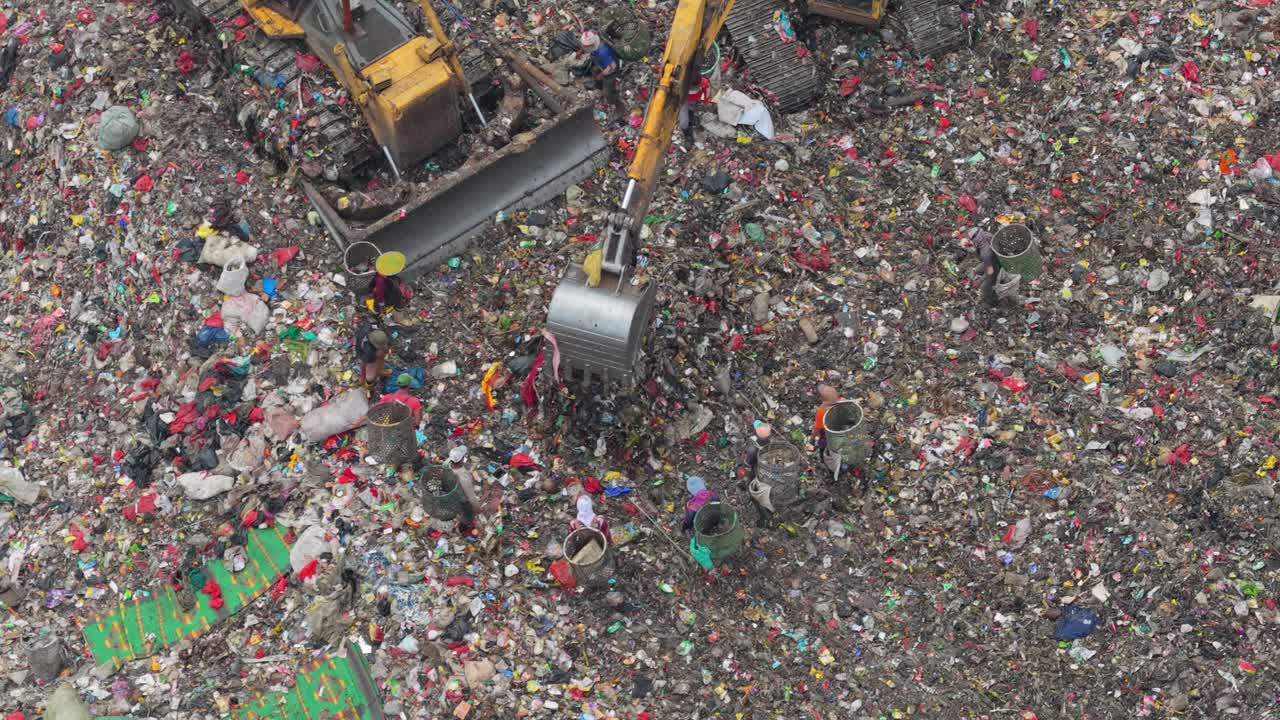 Bulldozer ed escavatore che spostano rifiuti presso la discarica di Bantar Gebang a Giacarta.