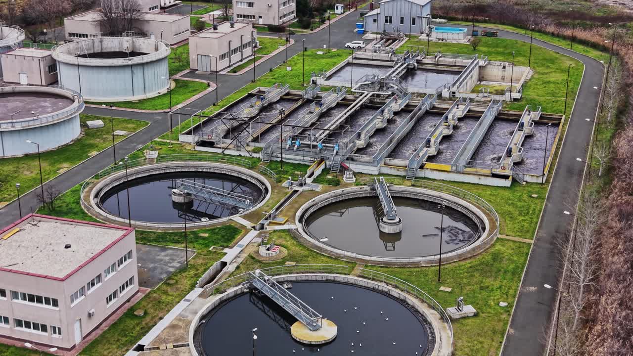 Planta de tratamiento de agua procesando residuos en una zona verde cerca de edificios