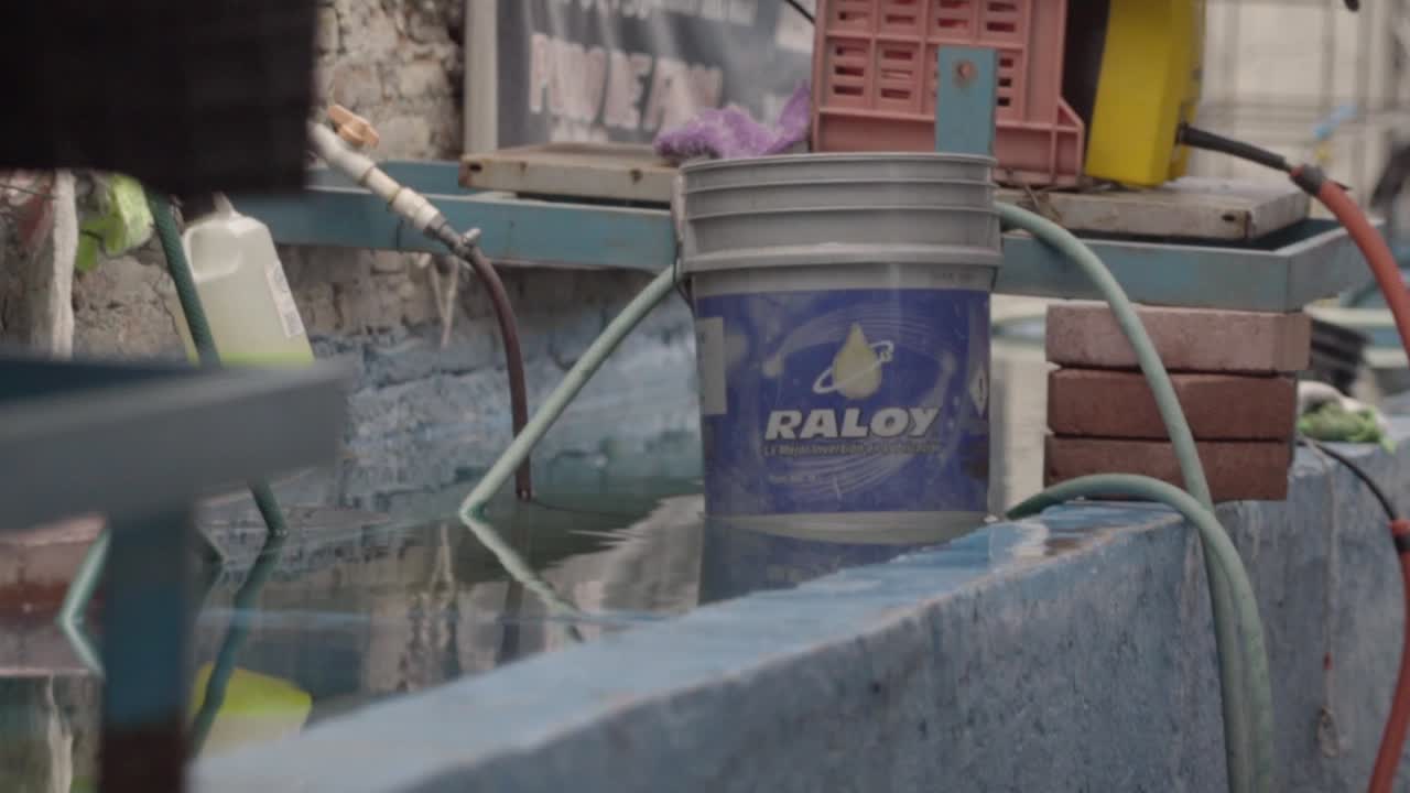 Raloy bucket near water with hoses and equipment in an outdoor workspace
