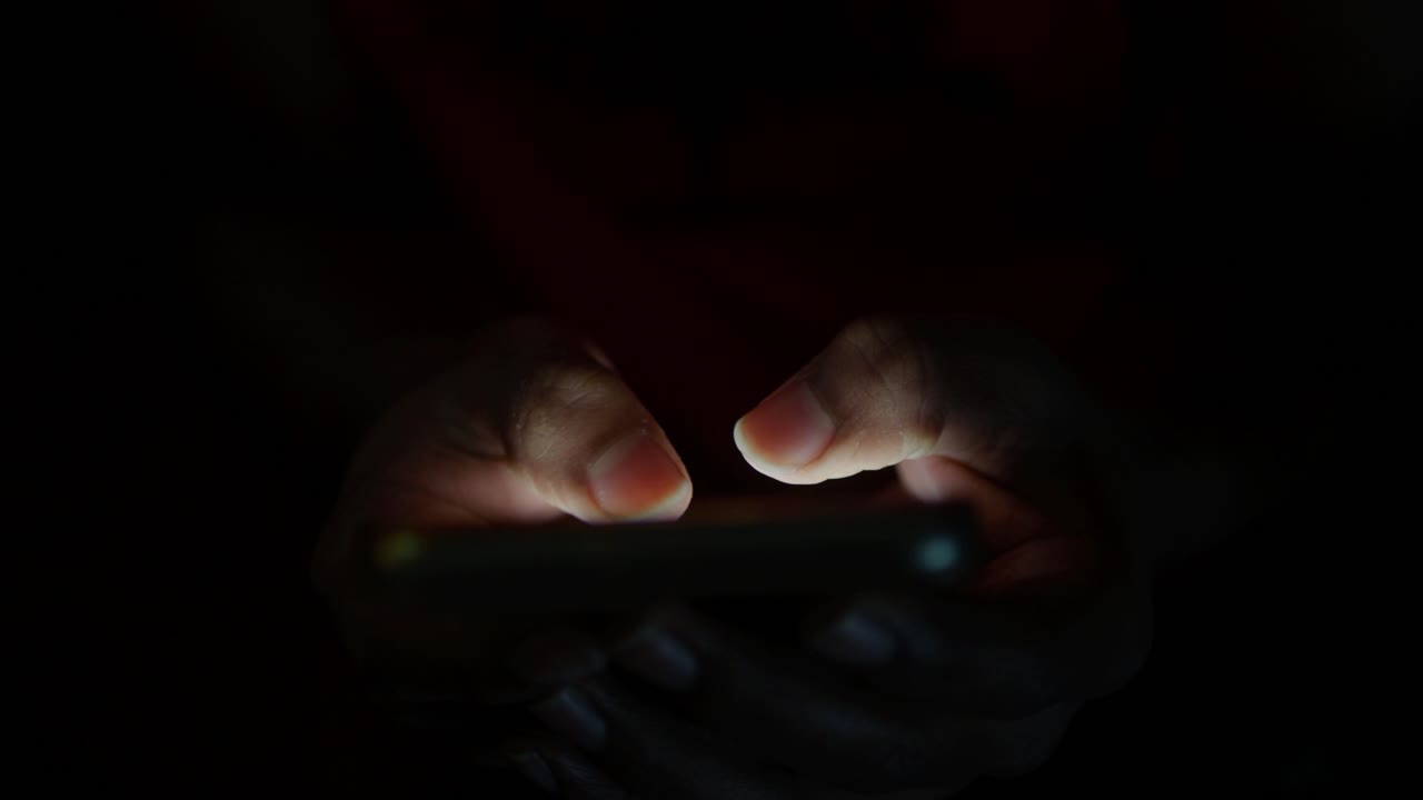 Hands Using a Smartphone in the Dark