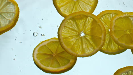 closeup fresh lemons underwater on white background. citrus slices floating.