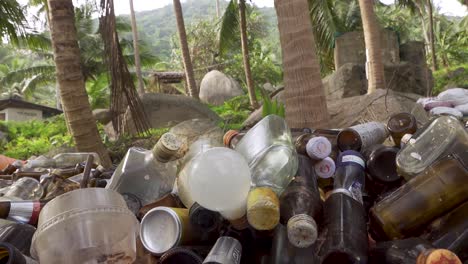 collected trash bottles piled up under palm trees near the beach, steady shot