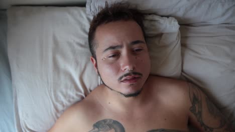 young man with tattoos crying in bed
